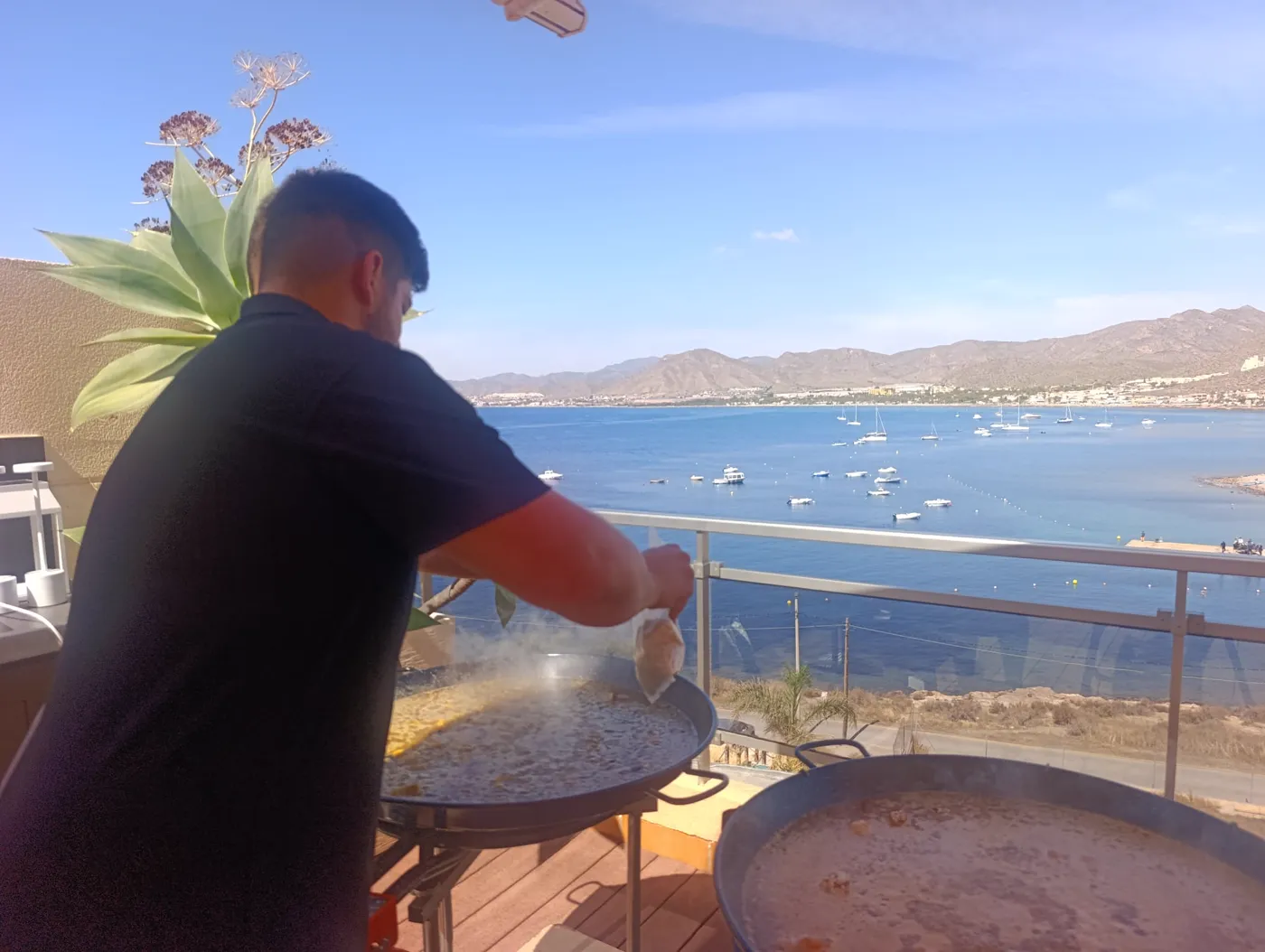 Pedro cocinando paellas en una terraza frente al mar