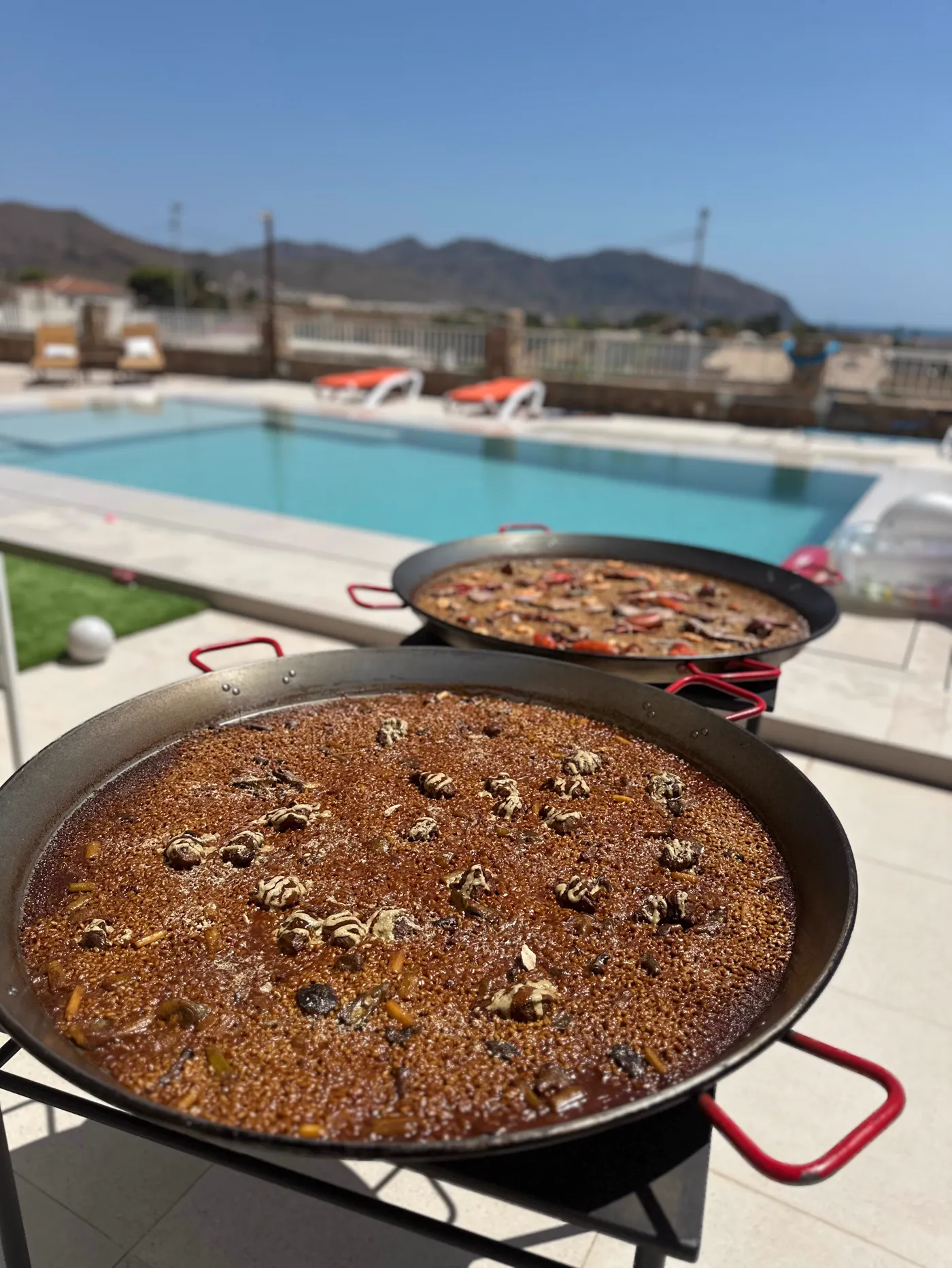 Dos paellas en marcha junto a la piscina