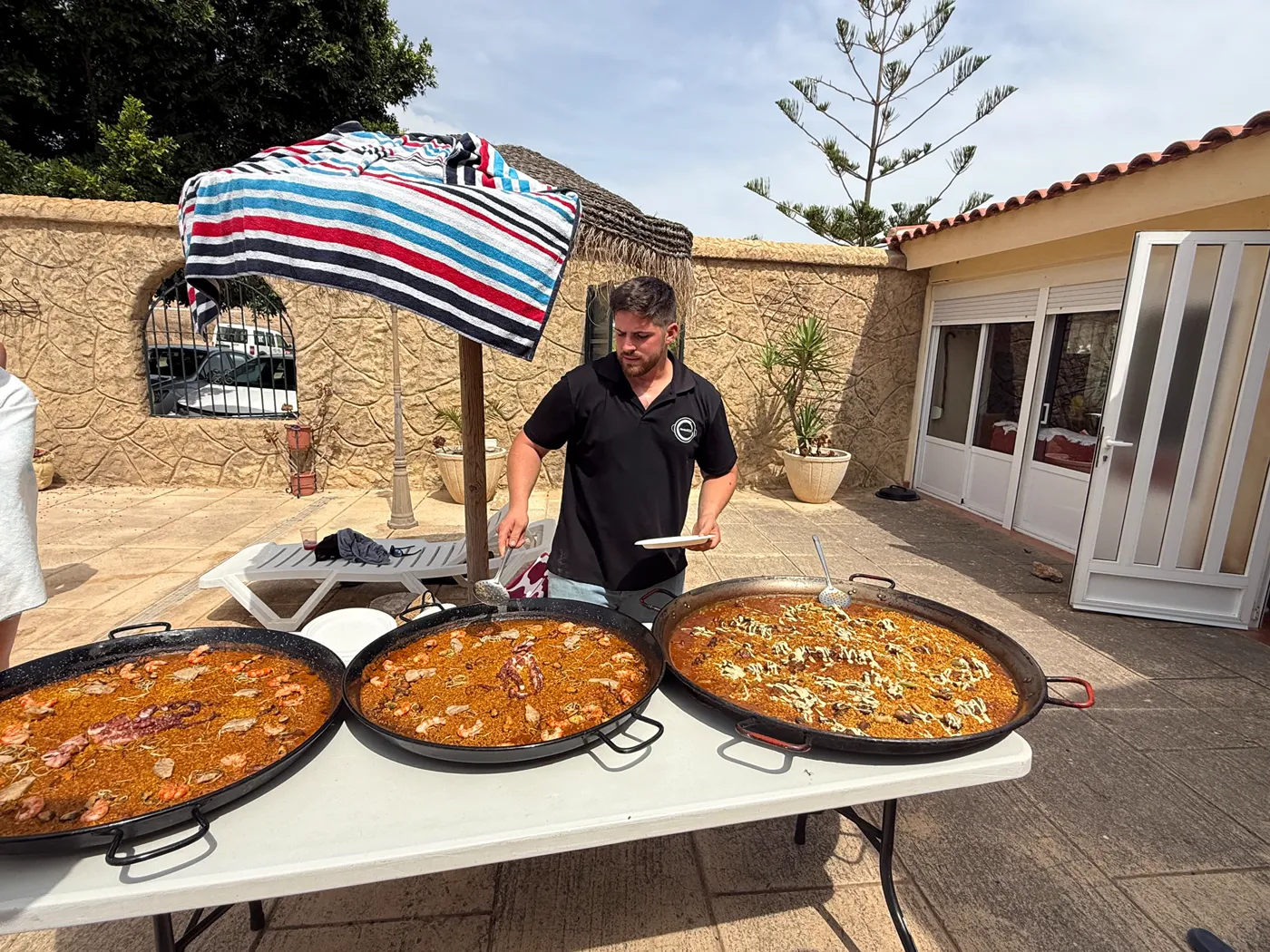 Pedro con tres paellas servidas en un patio