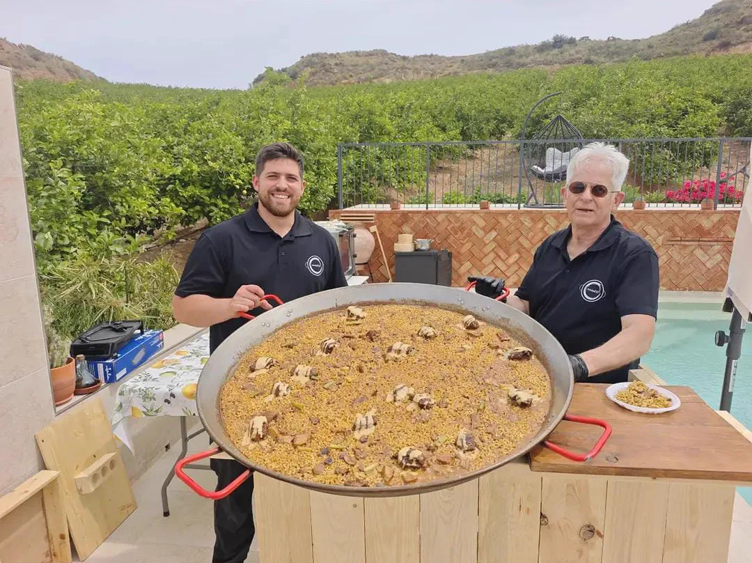 Pedro y su equipo con una paella grande en un evento privado junto a la piscina