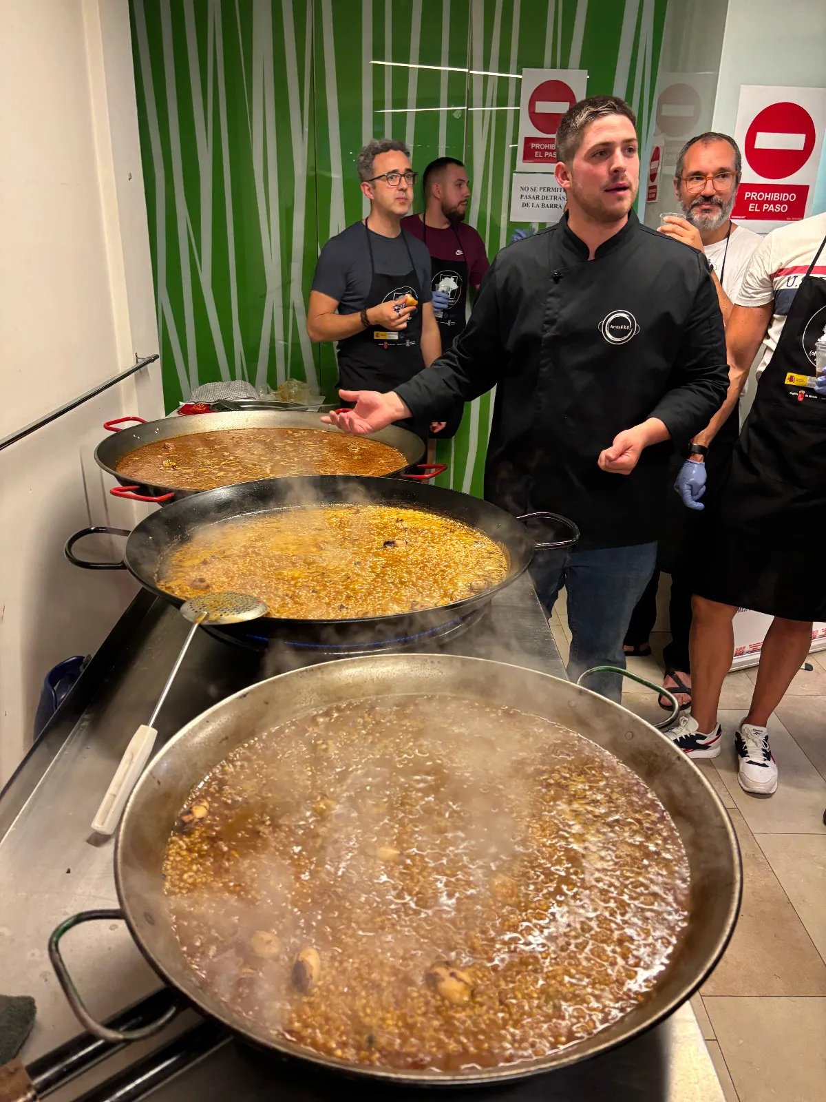Pedro explicando a los alumnos con tres paellas al fuego en un taller